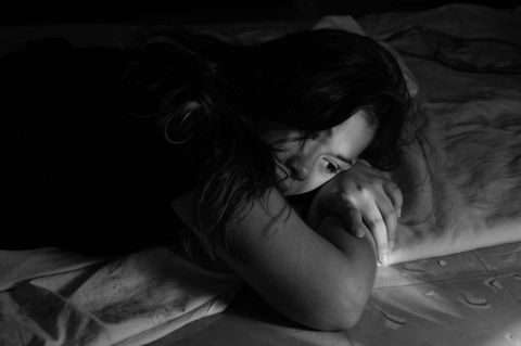 Woman lying down alone, feeling low on intimacy