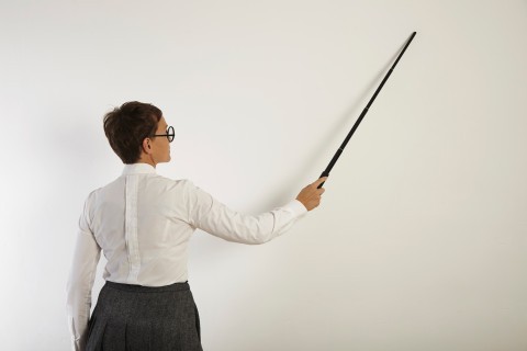 A female teacher standing sternly at her desk.