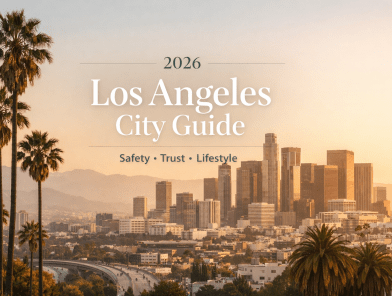 Golden hour over downtown Los Angeles skyline with palm trees in foreground, warm orange and pink sky reflecting off modern skyscrapers