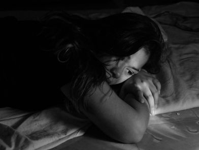 Woman lying down alone, feeling low on intimacy
